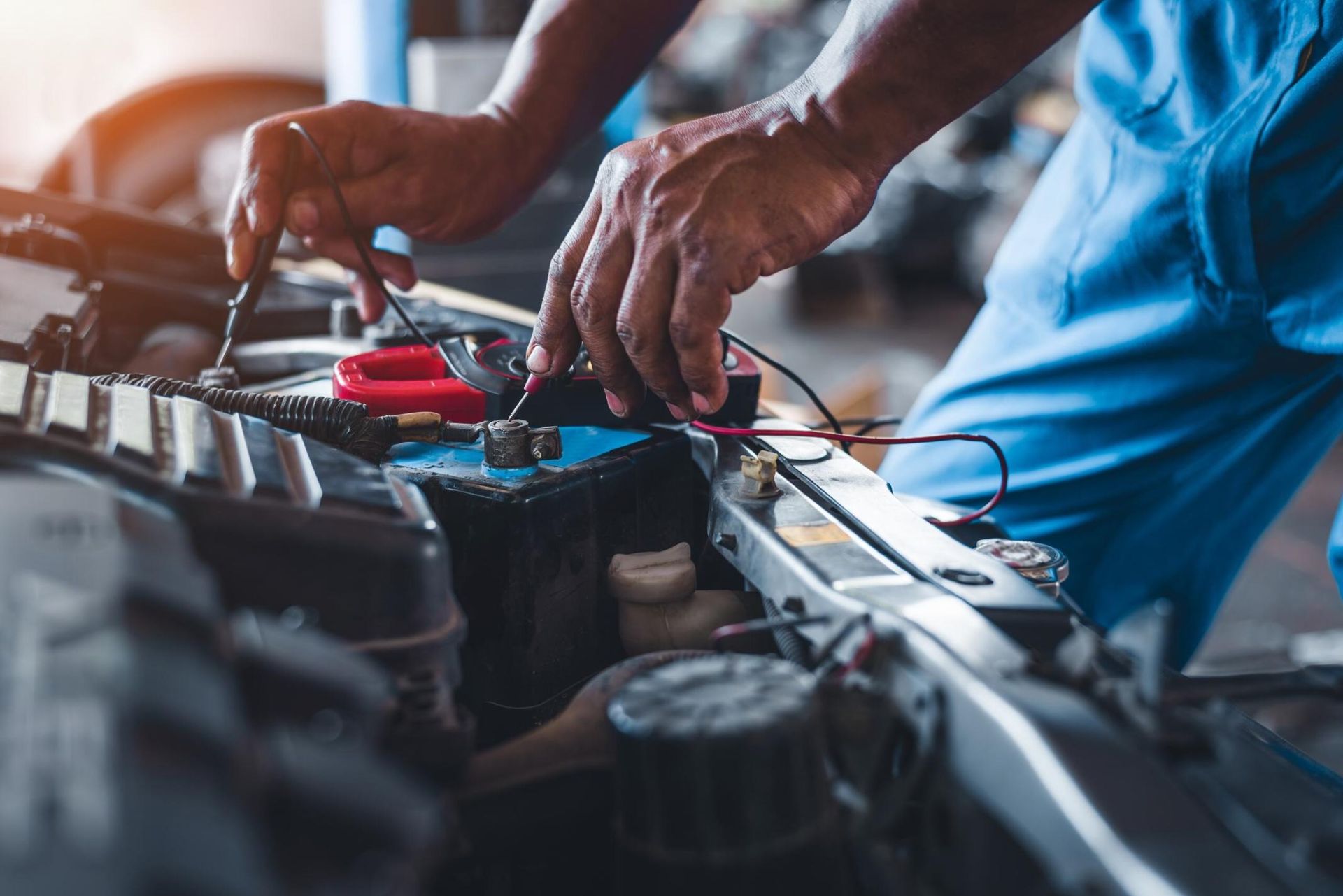 A Man is Working on a Car Battery in a Garage — Land Rover Spares In Mackay, QLD