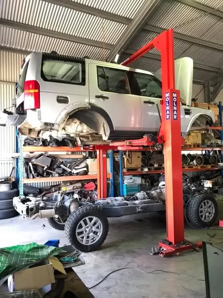 A Car is Sitting on Top of a Red Lift in a Garage — Land Rover Spares In Mackay, QLD