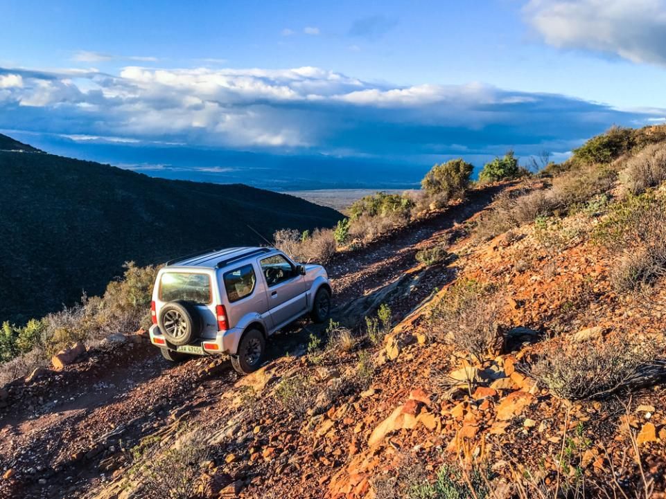 A White Suv is Driving Down a Dirt Road in the Mountains — Land Rover Spares In Mackay, QLD