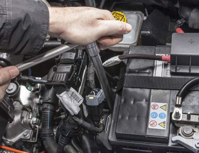 A Person is Working on a Car Battery With a Wrench — Land Rover Spares In Mackay, QLD