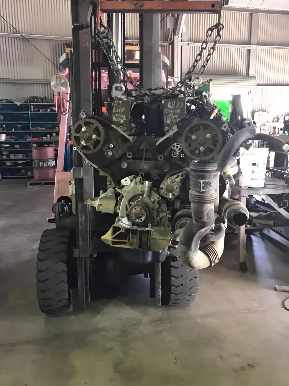 A Forklift is Lifting a Large Engine in a Garage — Land Rover Spares In Mackay, QLD