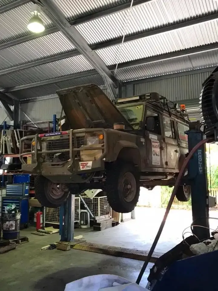 A Car is Sitting on a Lift in a Garage With Its Hood Open — Land Rover Spares In Mackay, QLD