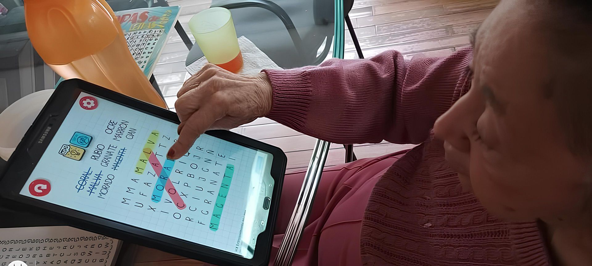 Una mujer está sentada en una mesa usando una tableta.