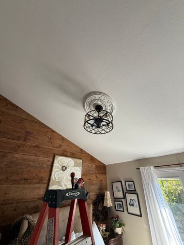 Bedroom with a wooden bed, nightstand, rocking chair, and ceiling fan. Natural light from a window.