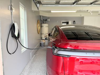 Gray electric SUV charging at a station outdoors.