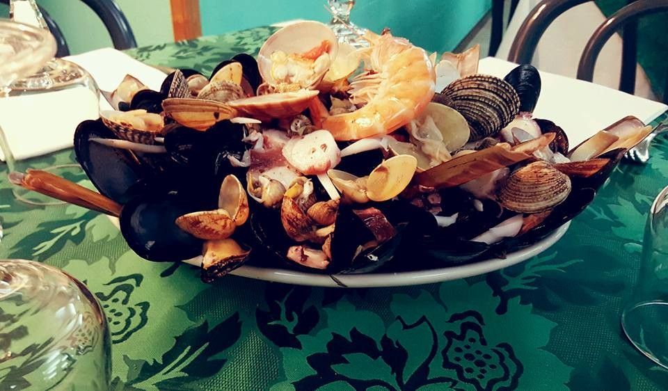 Piatto di frutti di mare misti con aragosta, cozze e vongole su una tovaglia verde.