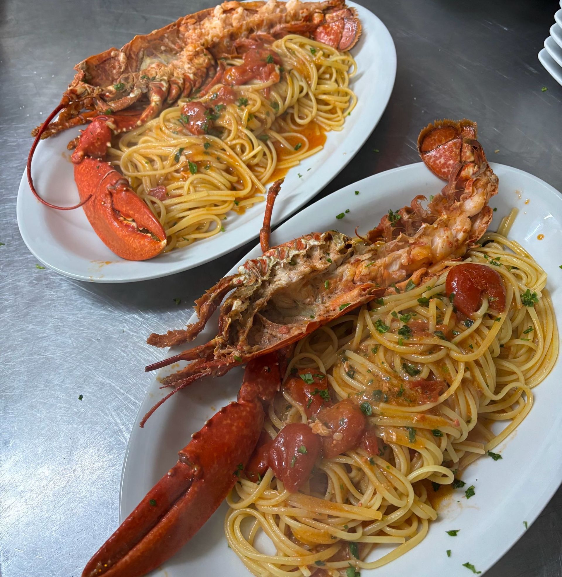 Due piatti di spaghetti all'astice su un tavolo di metallo.