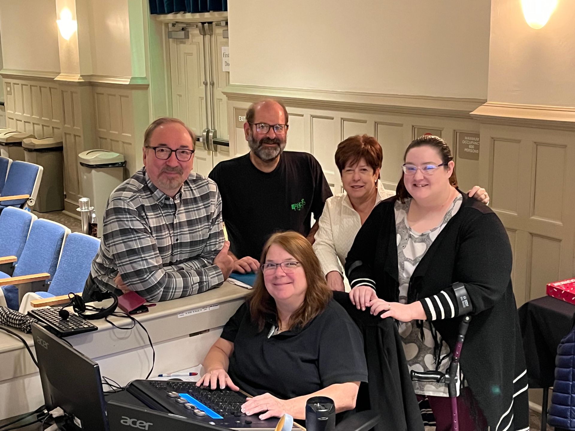 A group of people are posing for a picture in front of a computer.