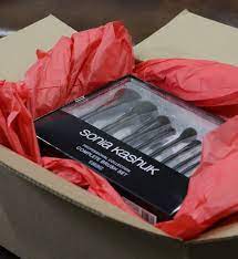A box filled with makeup brushes wrapped in red paper.