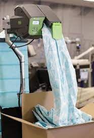 A machine is putting a piece of paper into a cardboard box.