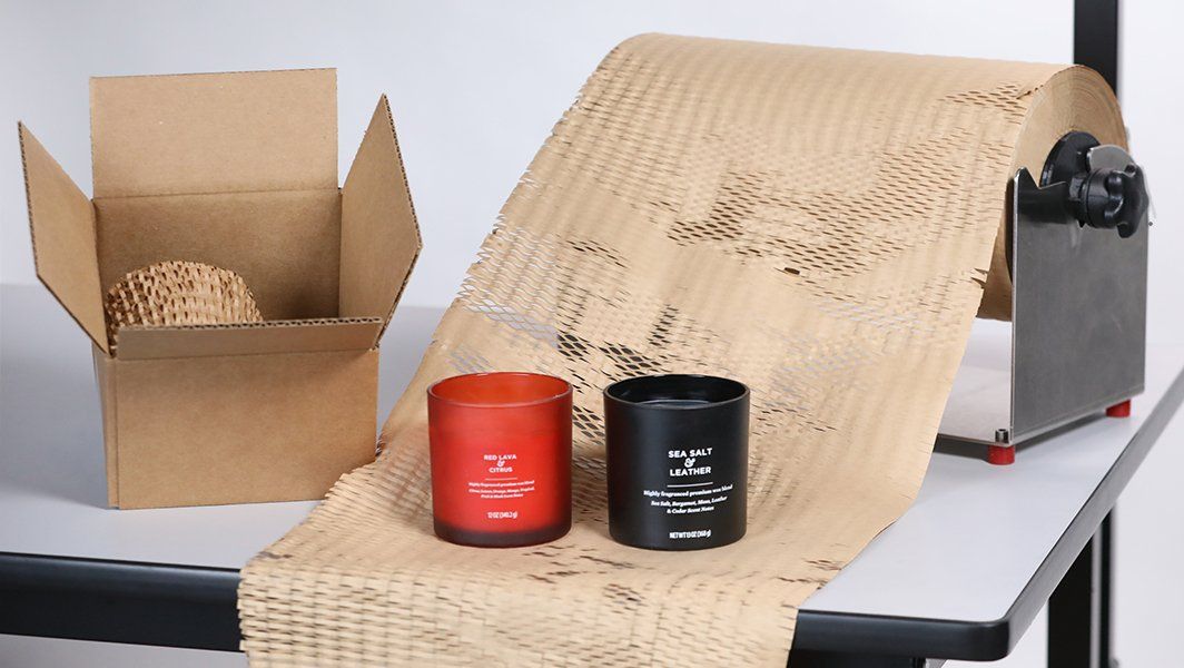Two candles are sitting on a table next to a cardboard box.