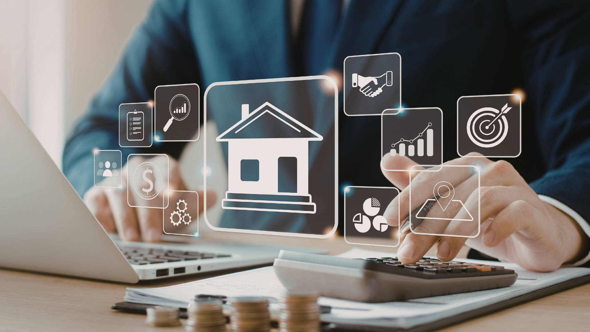 Hands using calculator and laptop with floating real-estate icons on a desk