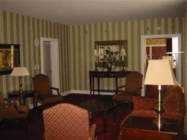 Living room with striped wallpaper, red sofas, chairs, lamps, and a coffee table