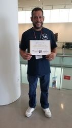 A man is standing in a room holding a certificate.