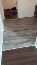 A room with a wooden floor and a vacuum cleaner in it.