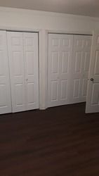 A bedroom with white closet doors and a wooden floor.