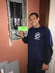 A man is standing in front of a electrical box holding a green card.