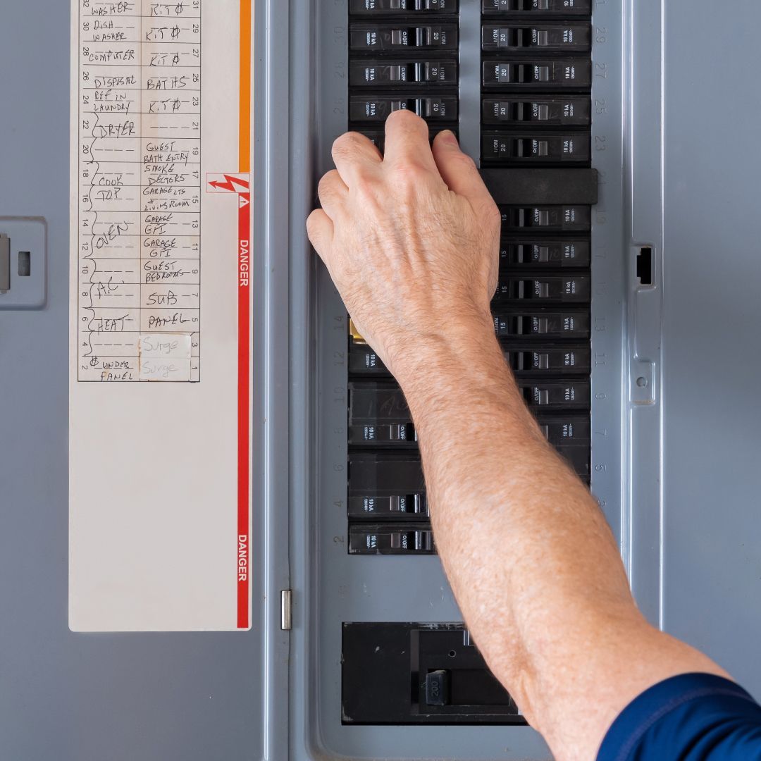 A person is pressing a button on an electrical panel