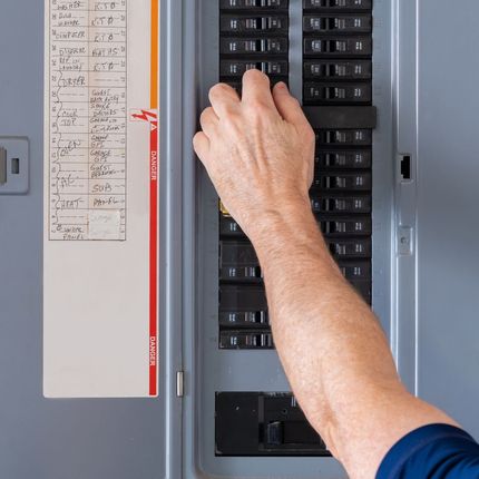A person is pressing a button on an electrical panel