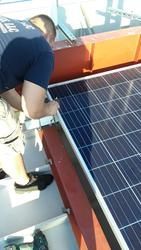 A man is working on a solar panel on a roof.