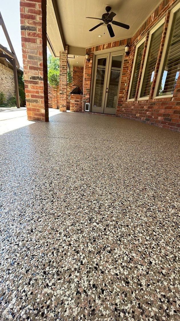 Covered brick porch with speckled terrazzo floor, ceiling fan, windows, and brick columns.