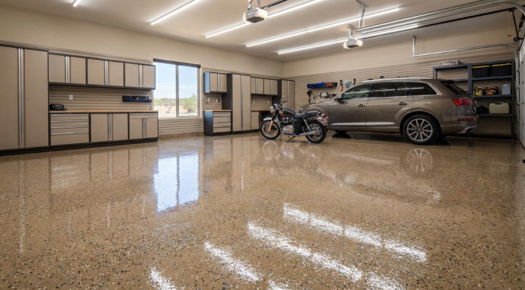 Spacious garage with cabinets, motorcycles, a silver SUV, and polished speckled floor under bright lights