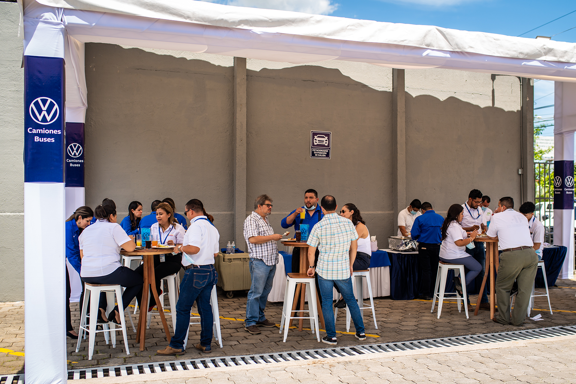 Un grupo de personas están sentadas en mesas bajo una carpa.