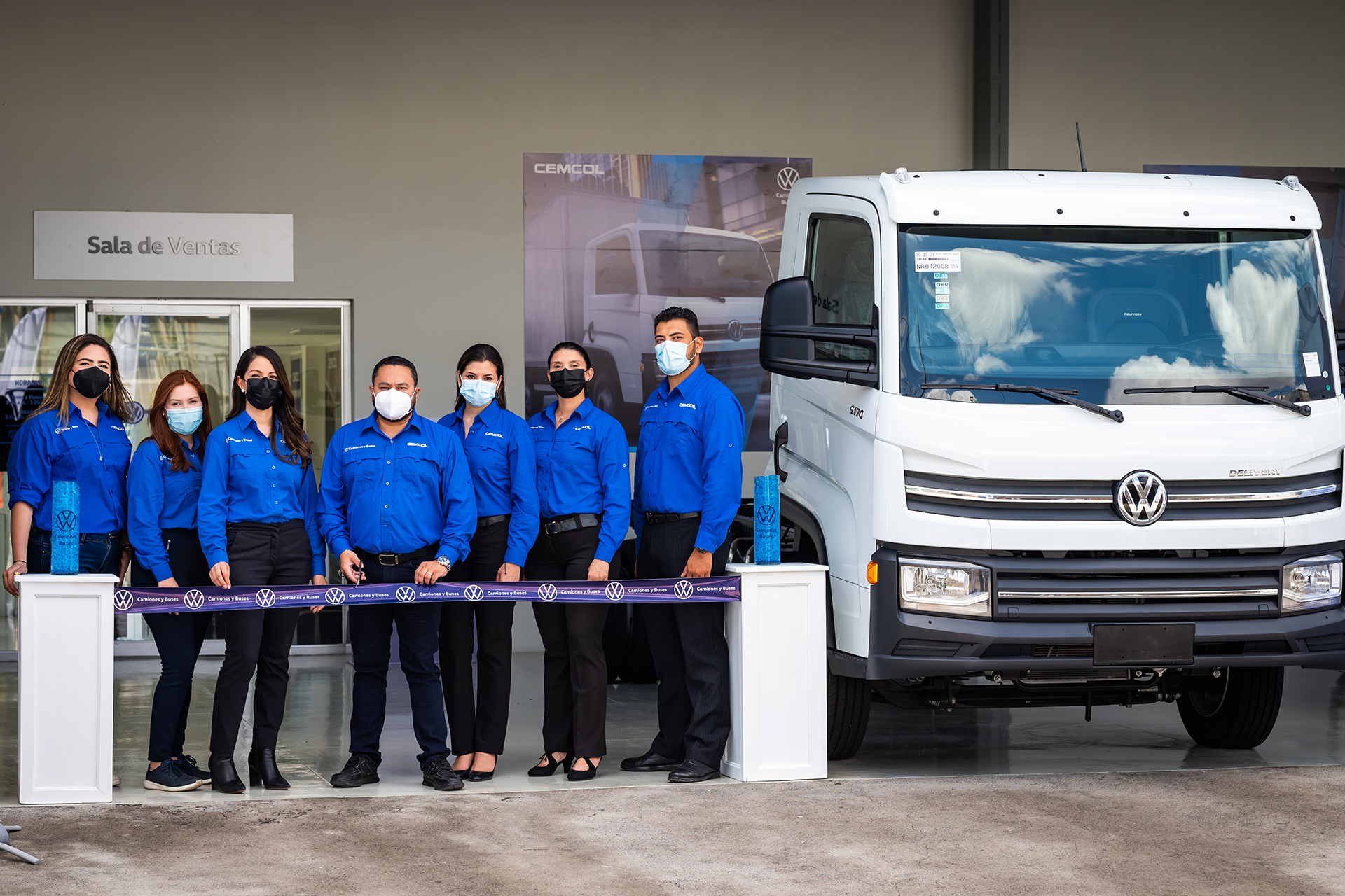 Un grupo de personas con máscaras se encuentran frente a una camioneta blanca.