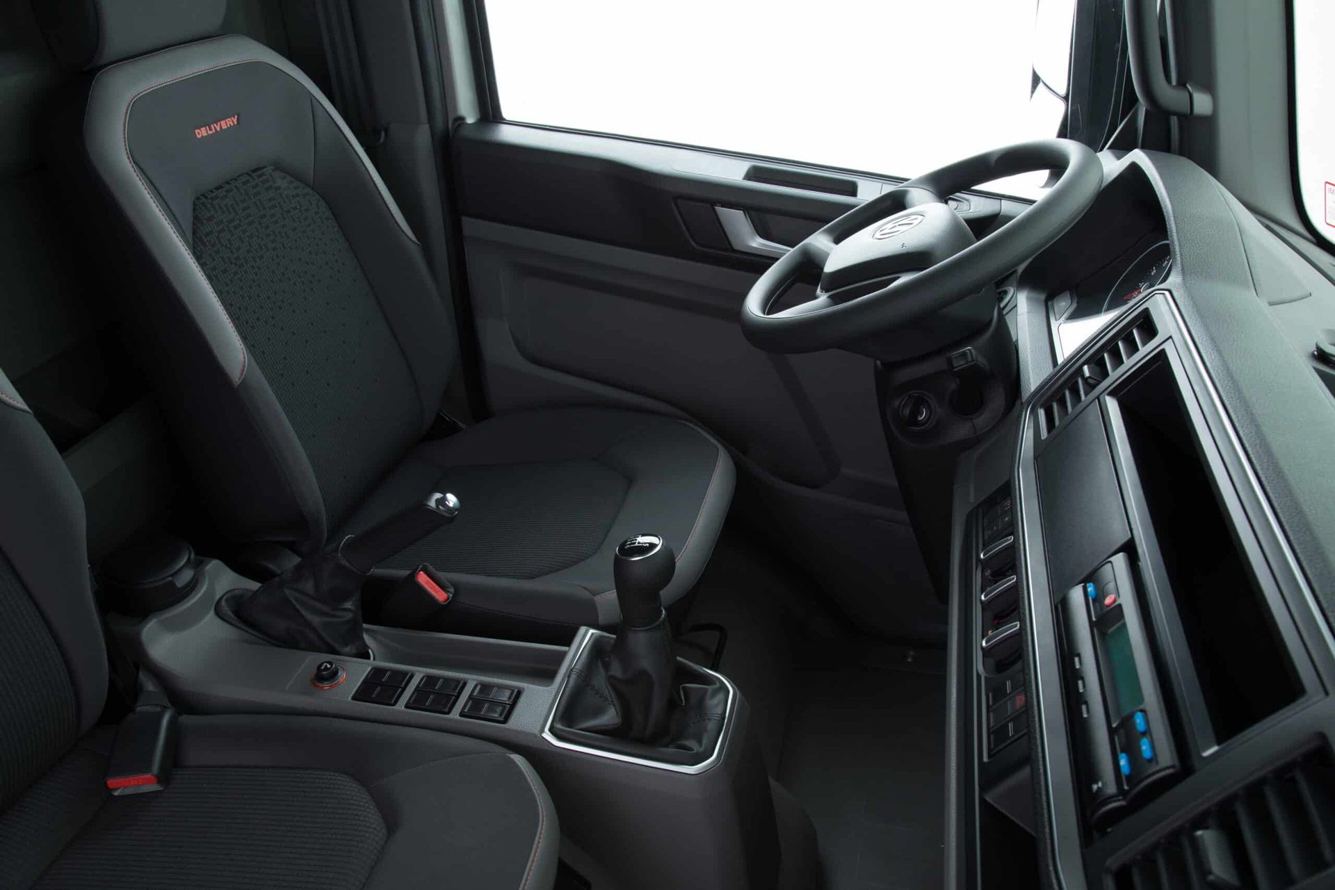 El interior de un camión volkswagen con asientos negros y un volante.