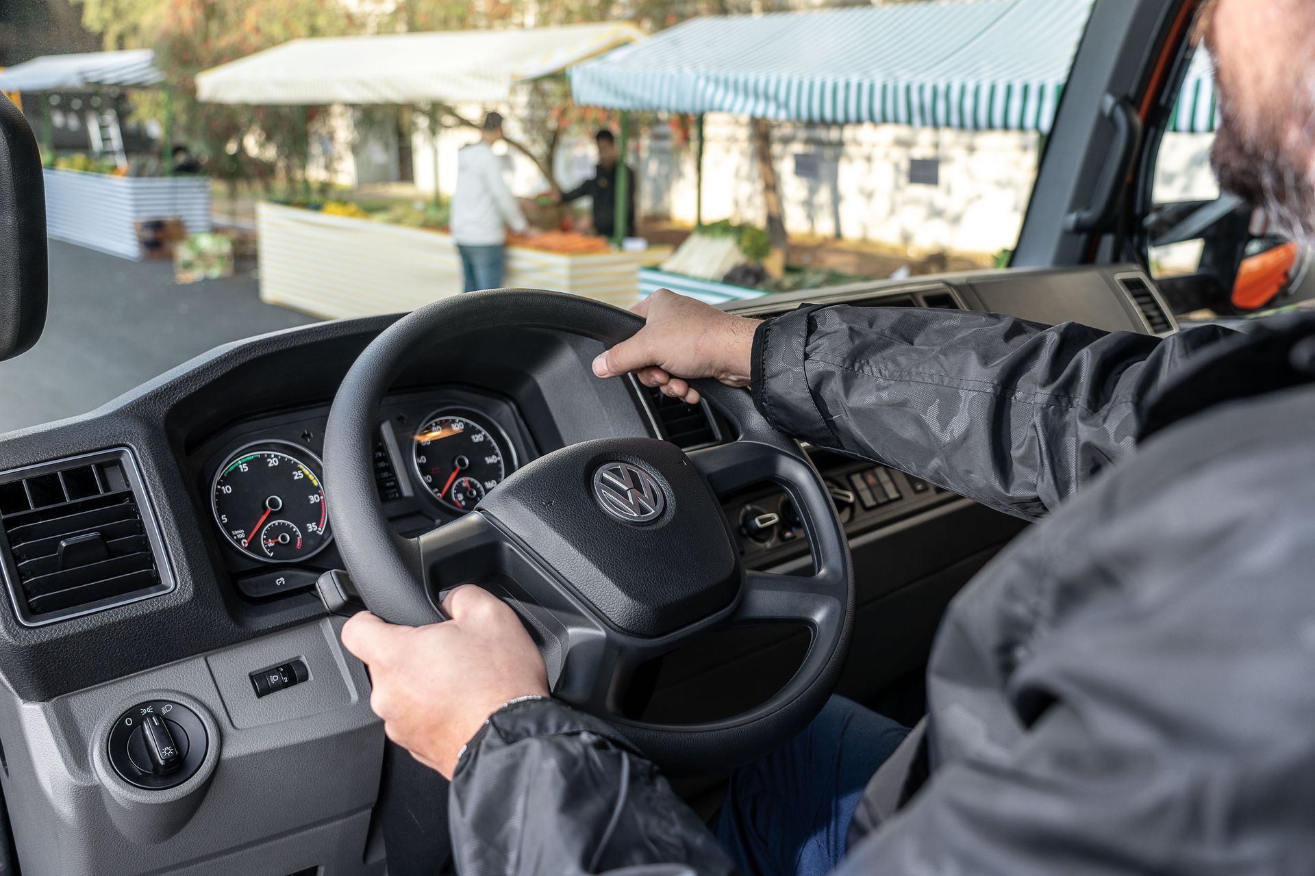 Un hombre conduce una camión Volkswagen con las manos en el volante.