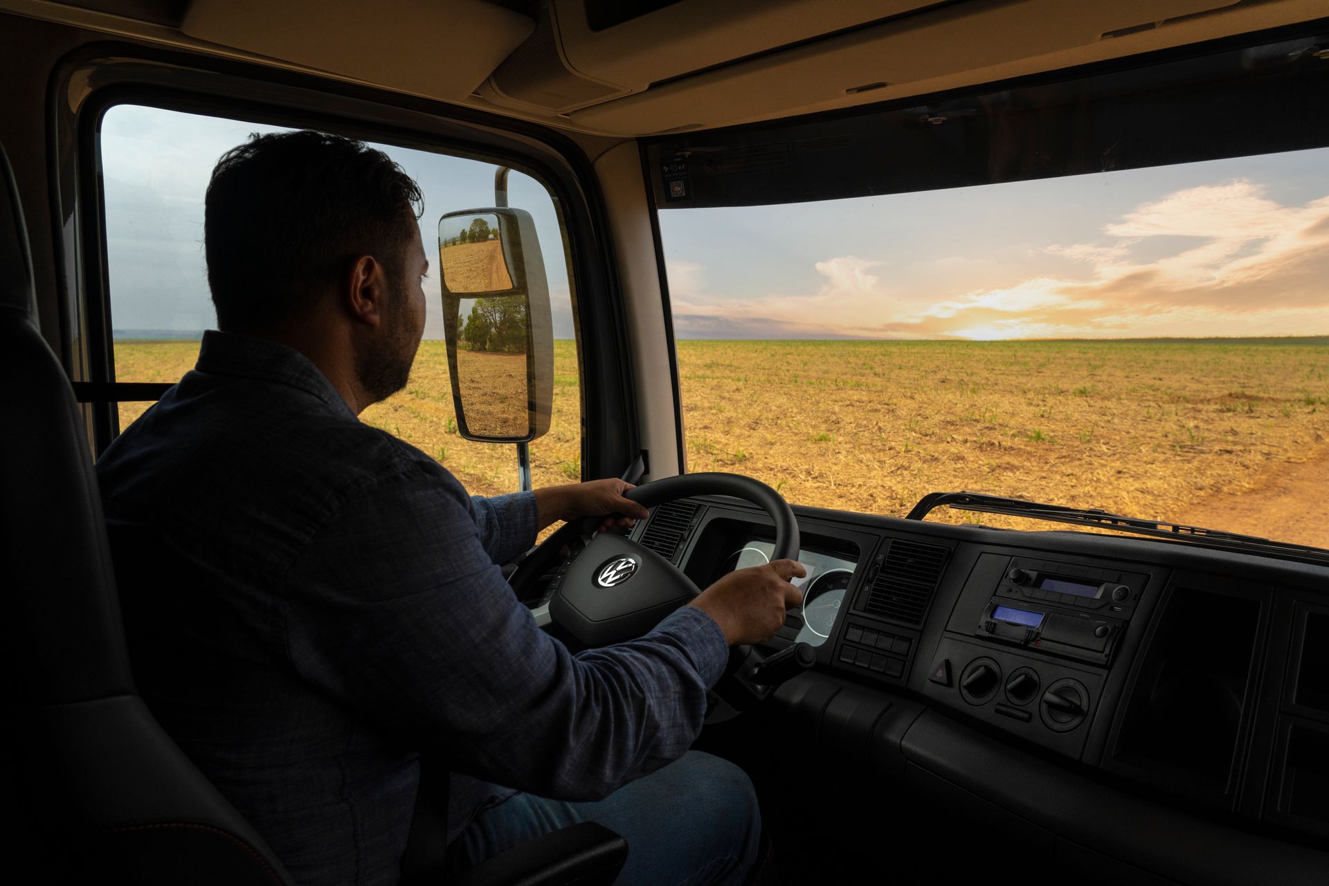 Un camión volkswagen circula por un camino de tierra entre campos de caña de azúcar.