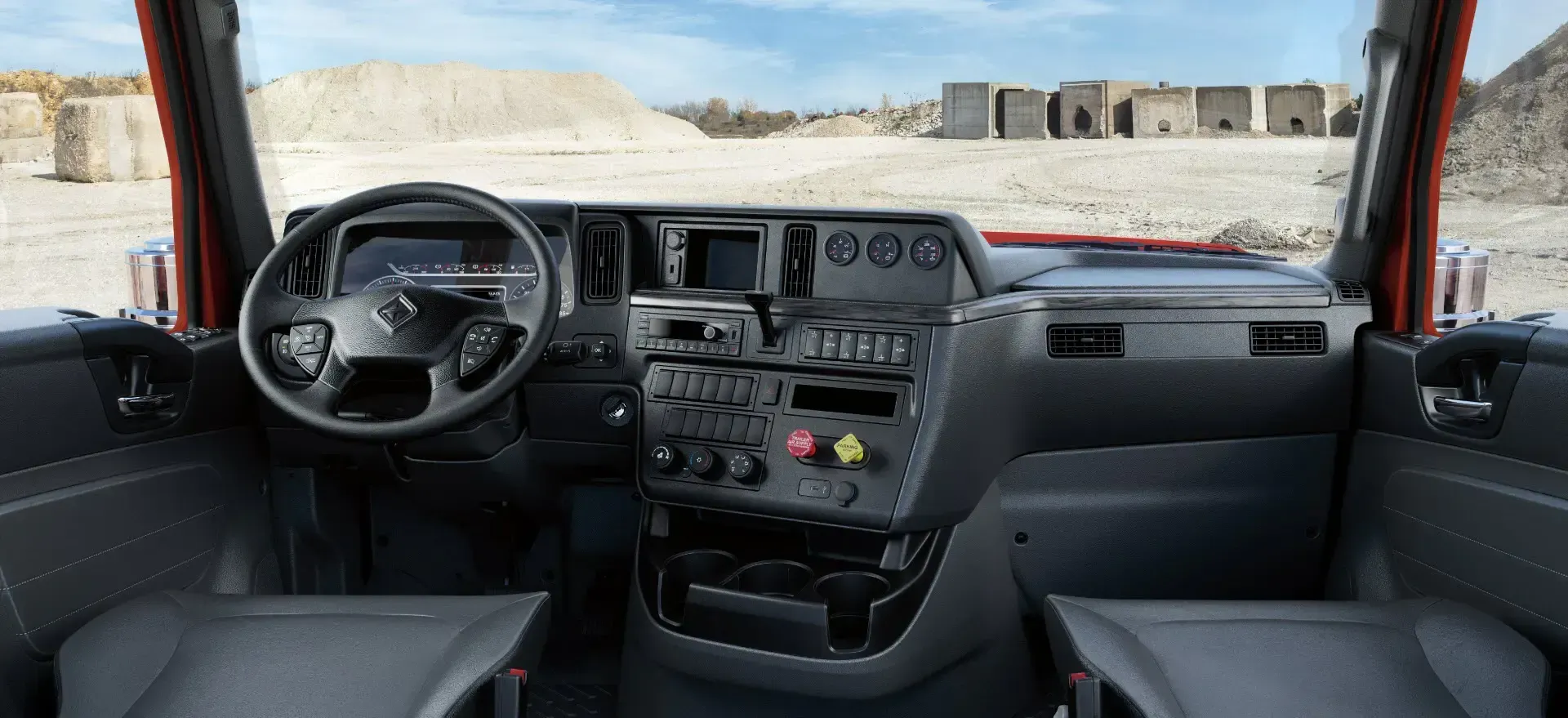 El interior de un camión con volante y tablero de instrumentos.
