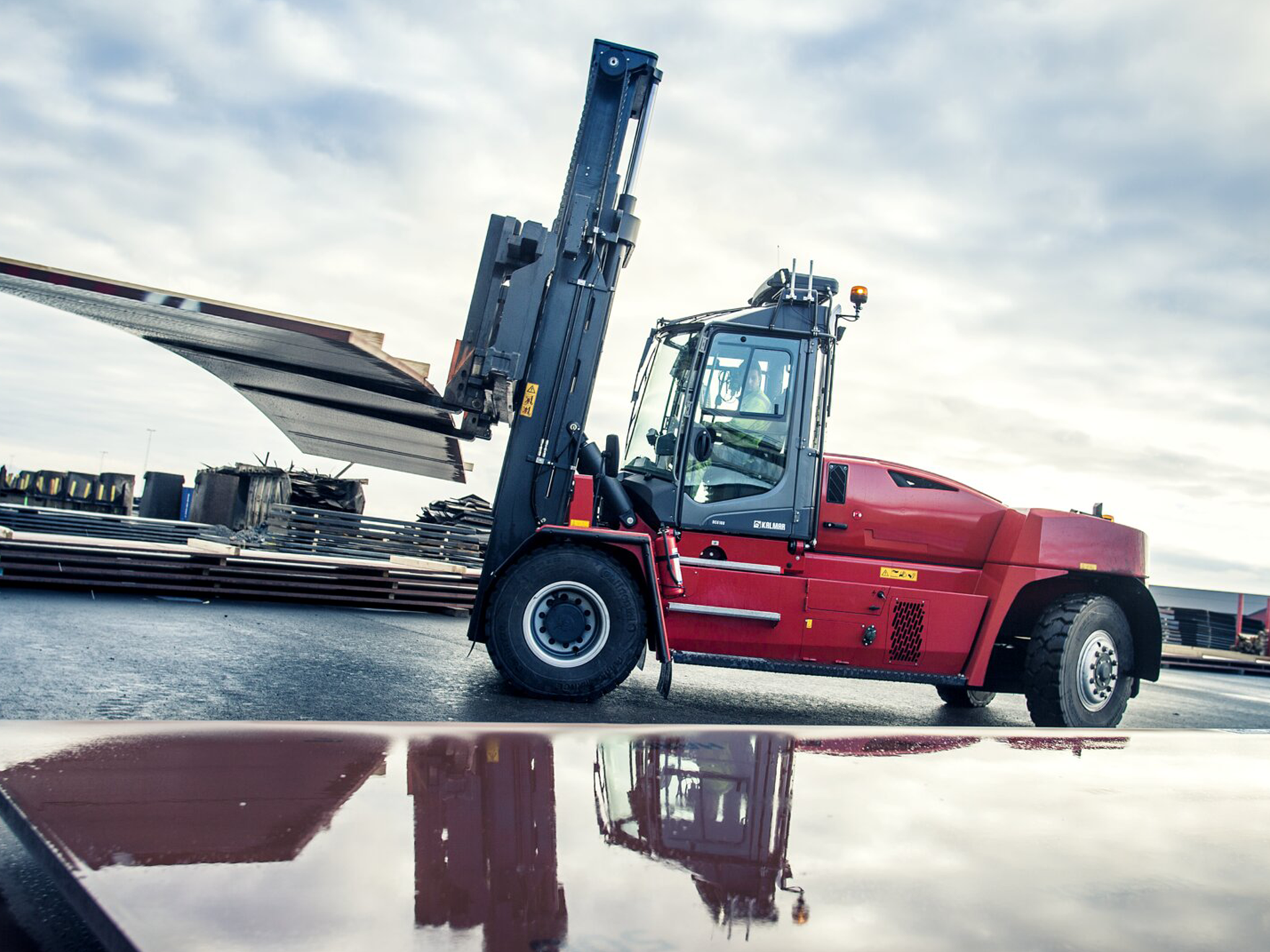 Una carretilla elevadora roja transporta una gran pieza de metal.