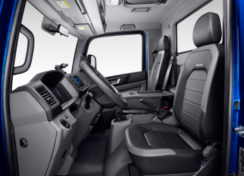 El interior de un camión volkswagen con asientos negros y un volante.