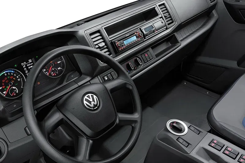 El interior de un camión volkswagen con asientos negros y un volante.