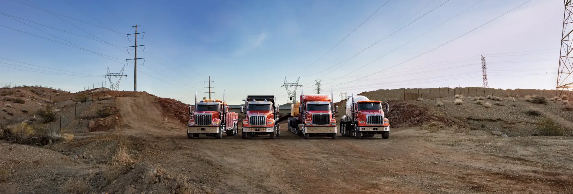 Un grupo de camiones están estacionados al costado de un camino de tierra.