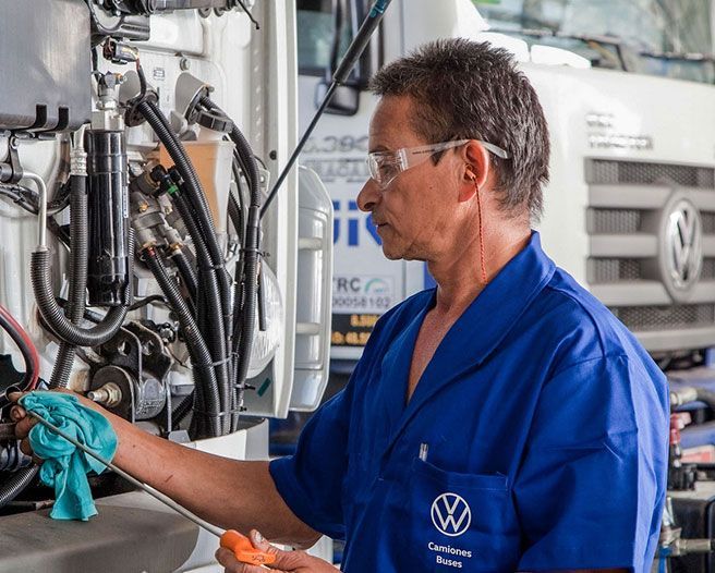 Un hombre con una camisa azul está trabajando en un camión.
