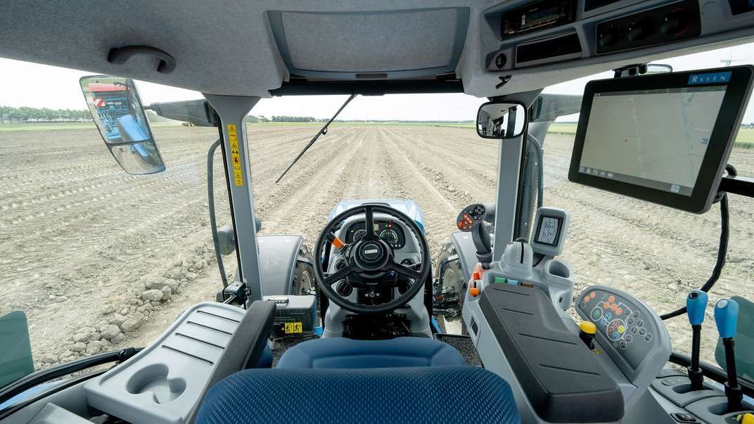 El interior de un tractor con un campo al fondo.
