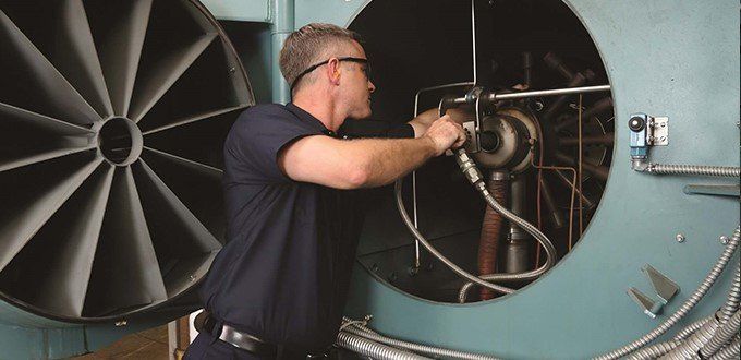 Un hombre está trabajando en una máquina con un ventilador en el fondo.