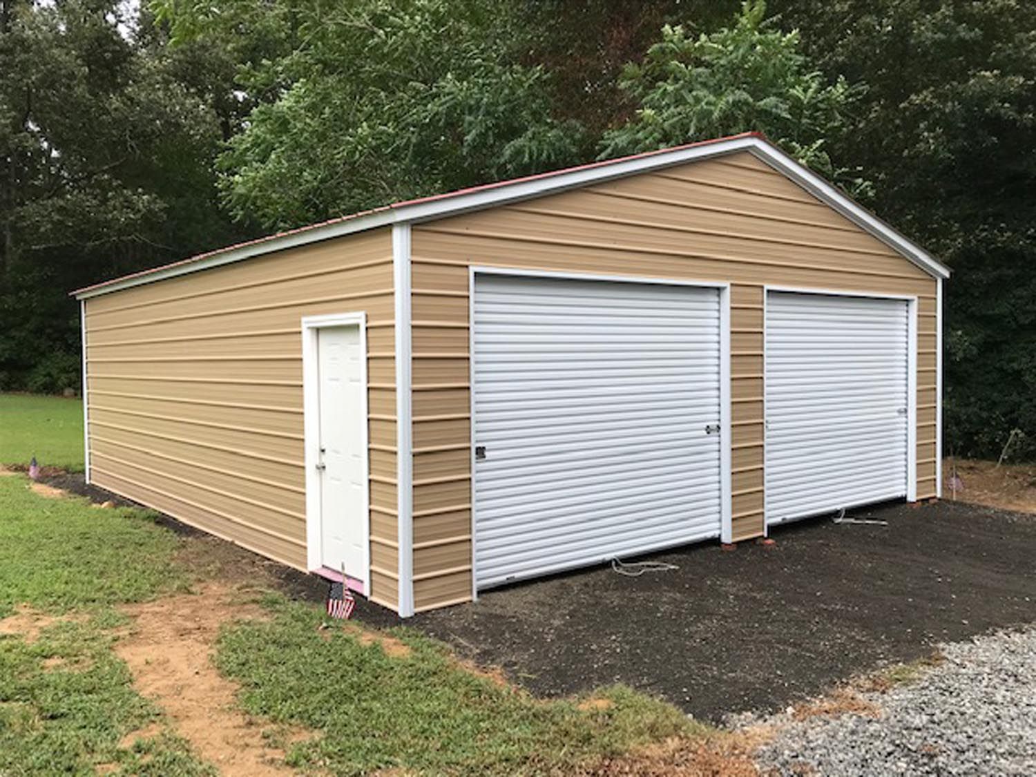 A tan garage with two white garage doors and a white door.