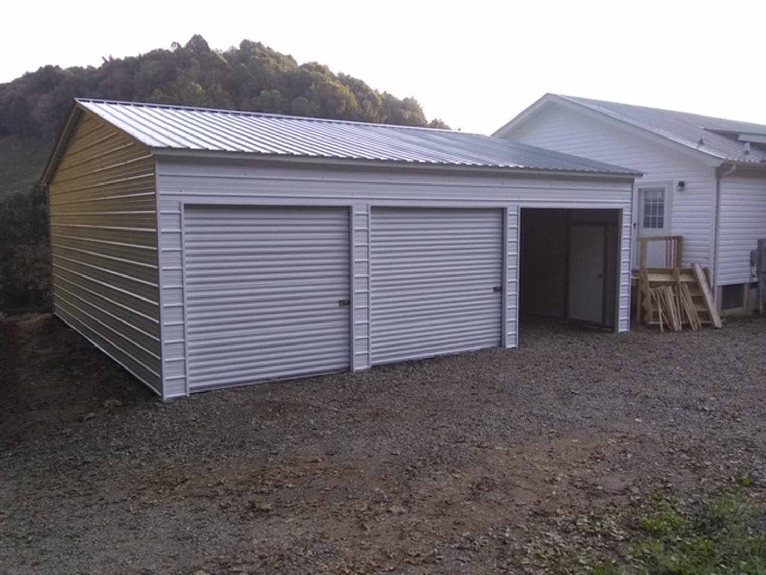 A garage with two roller doors and a white house in the background