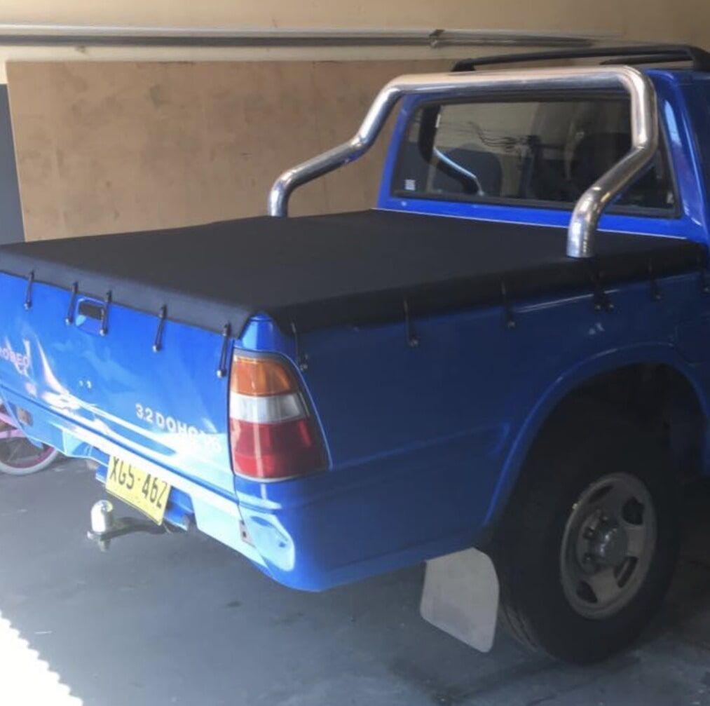 A Blue Truck with A Black Cover on The Bed Is Parked in A Garage - Quality Canvas Products In Illawarra, NSW