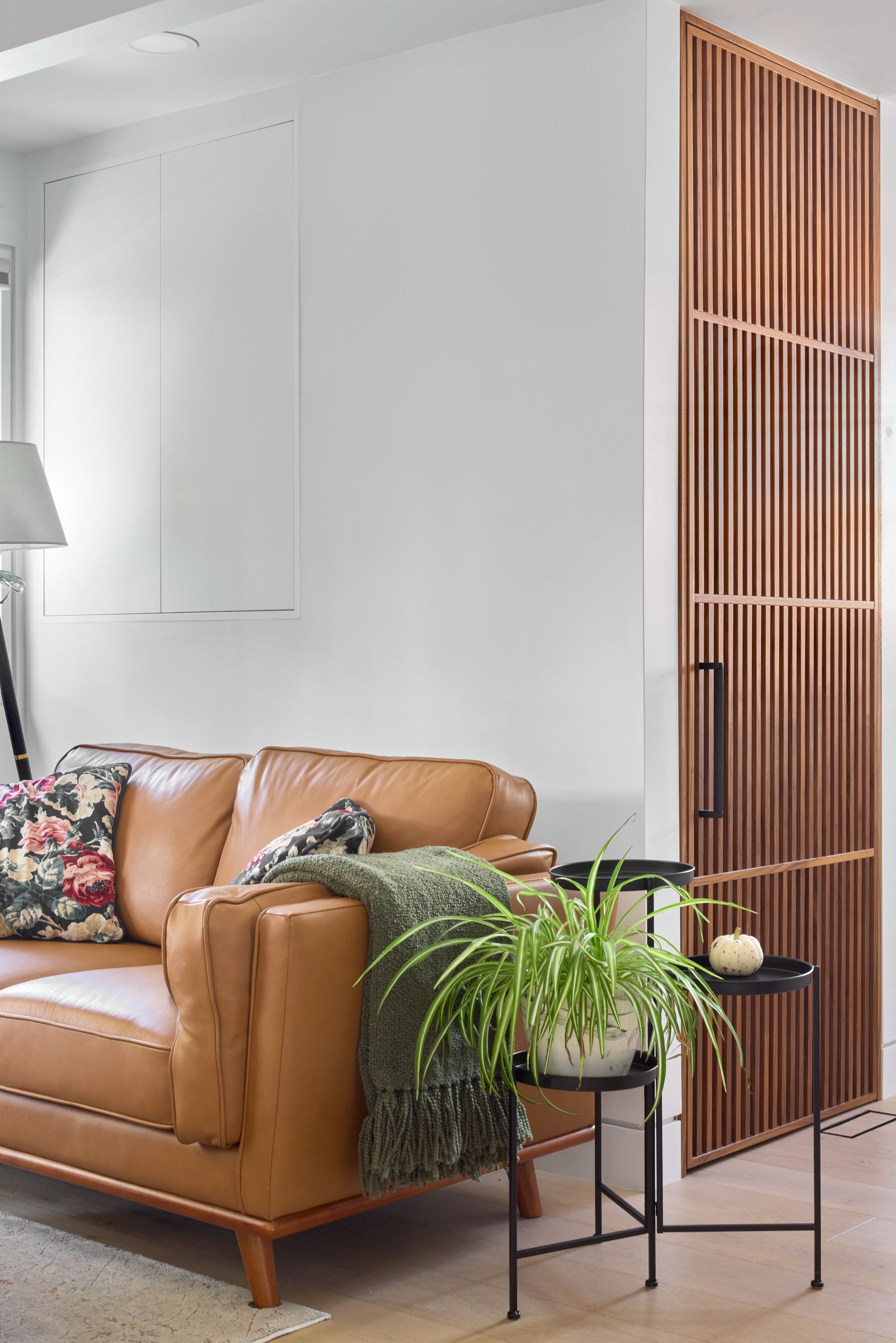 A living room with a brown leather couch and a plant on a table.