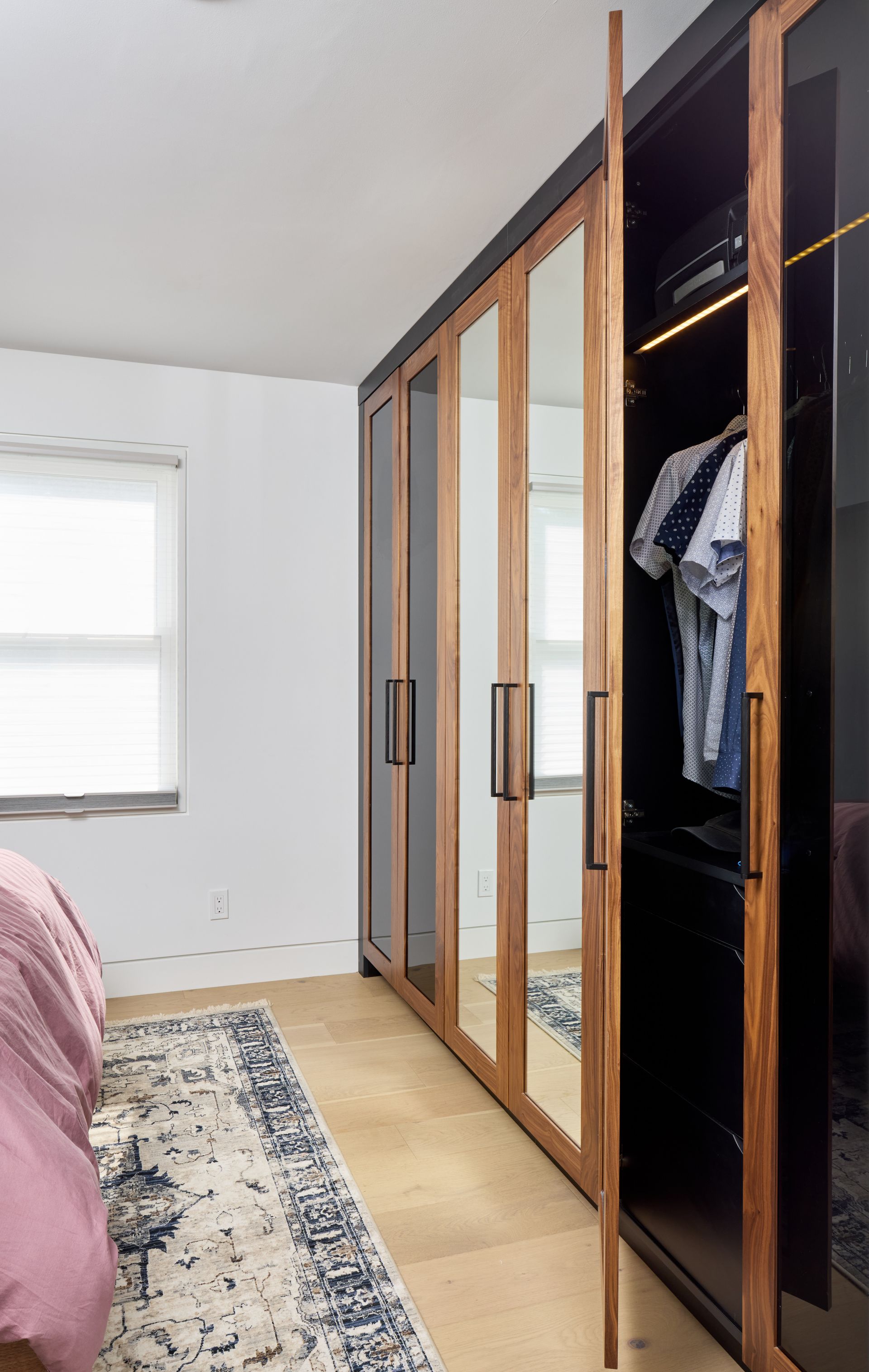 A bedroom with a bed and a closet with clothes in it
