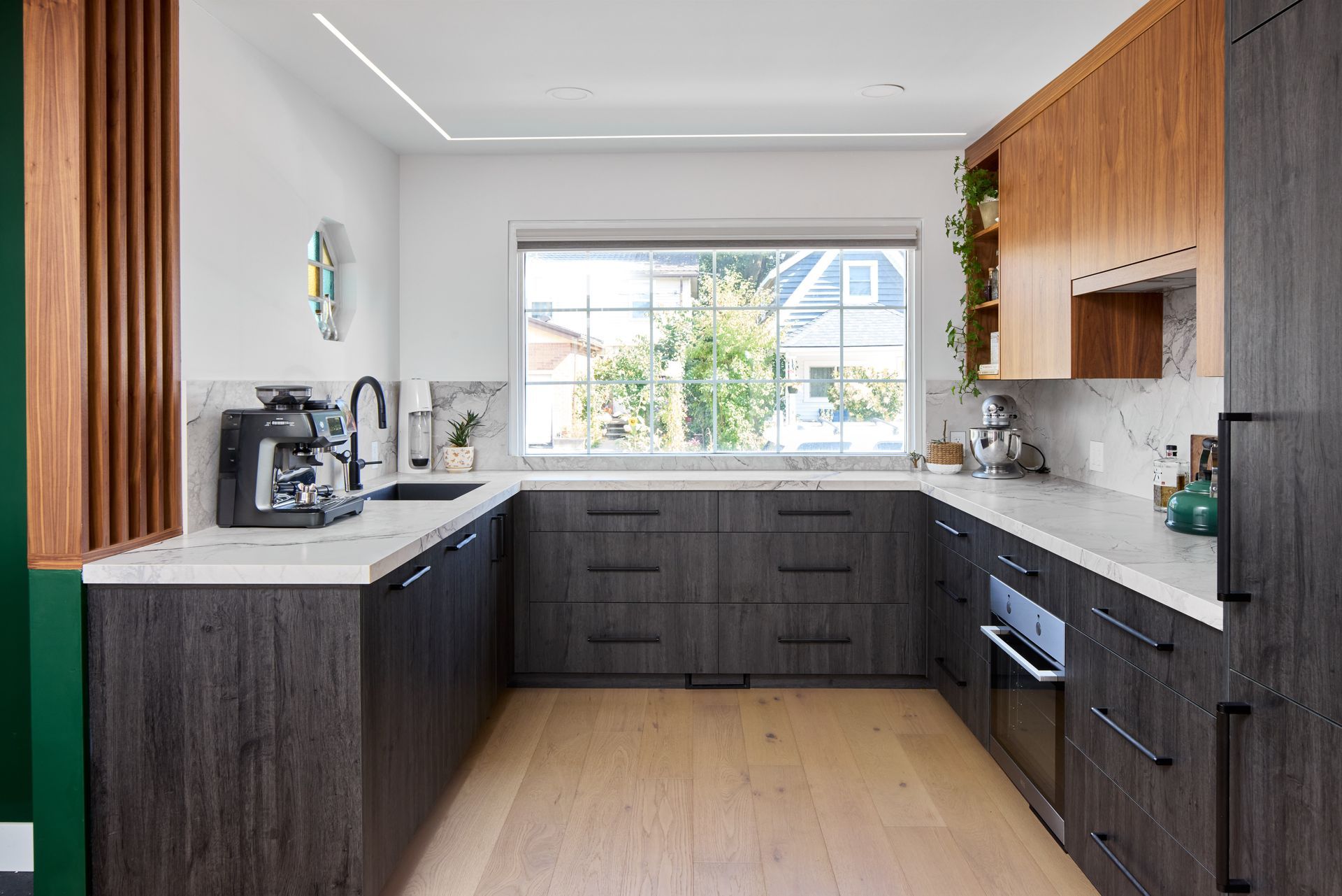 A kitchen with wooden cabinets and a large window.