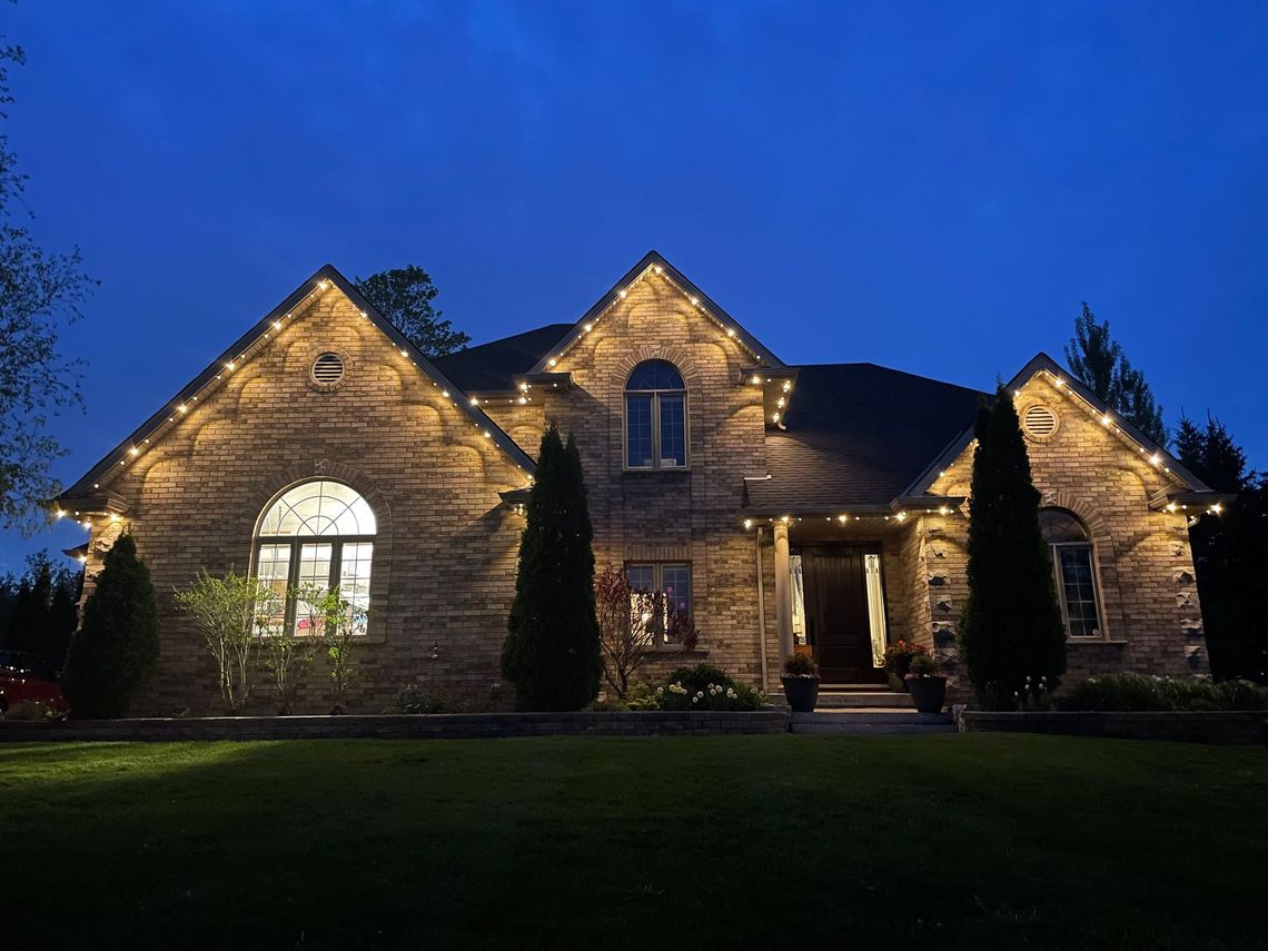 A large brick house is lit up at night with christmas lights.
