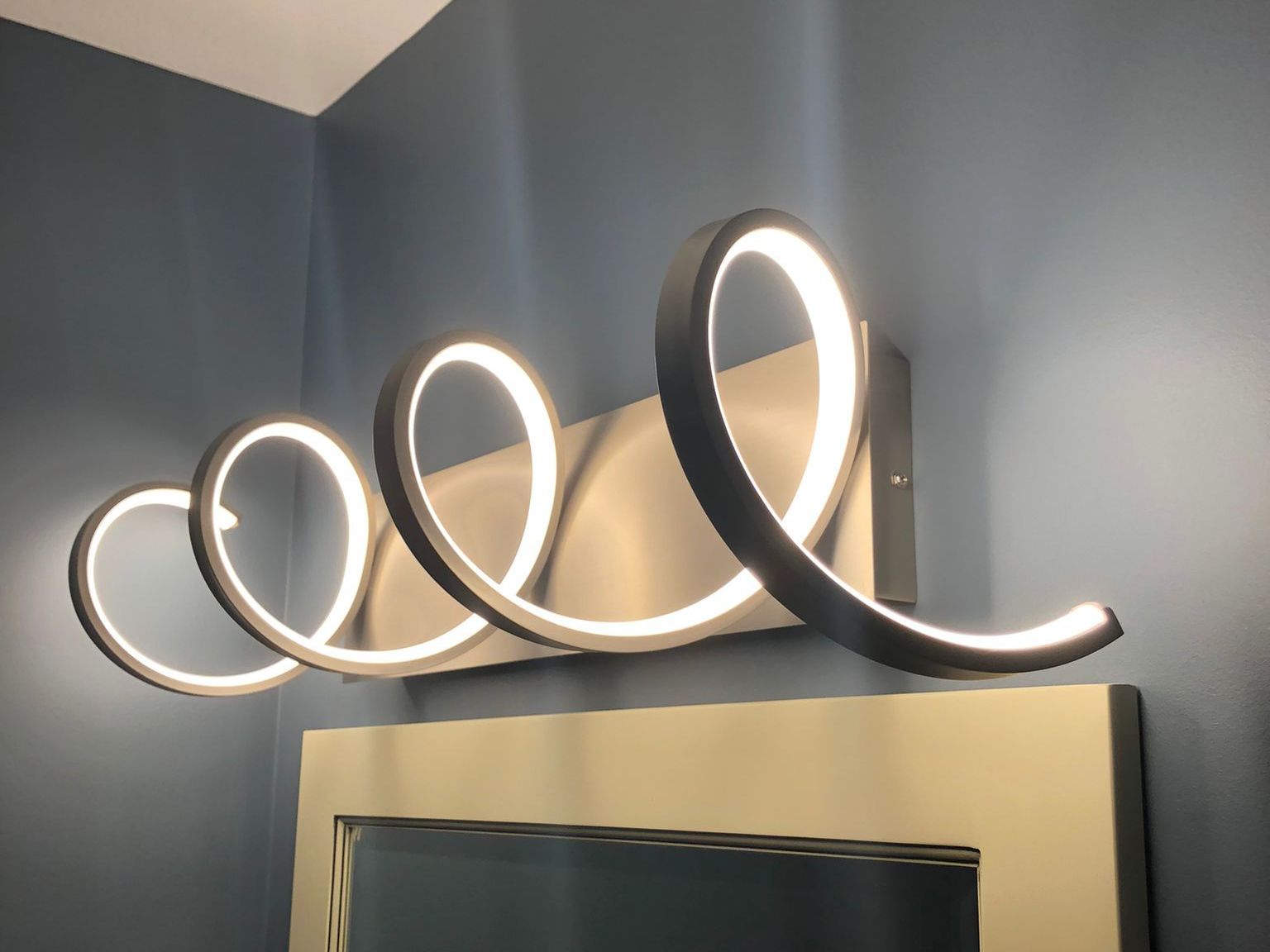 A bathroom vanity light with a spiral design on it