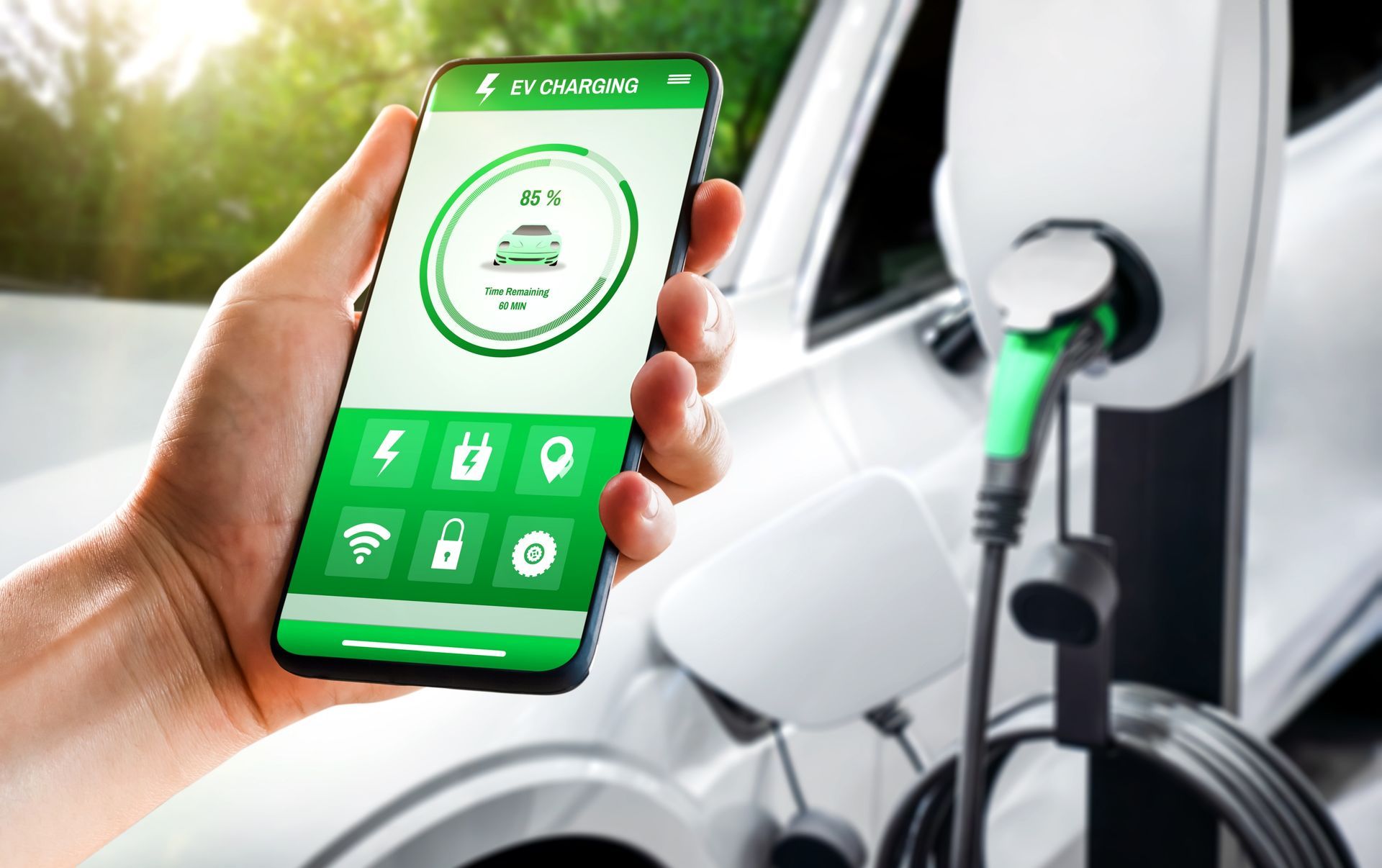 A person is holding a cell phone in front of an electric car being charged.