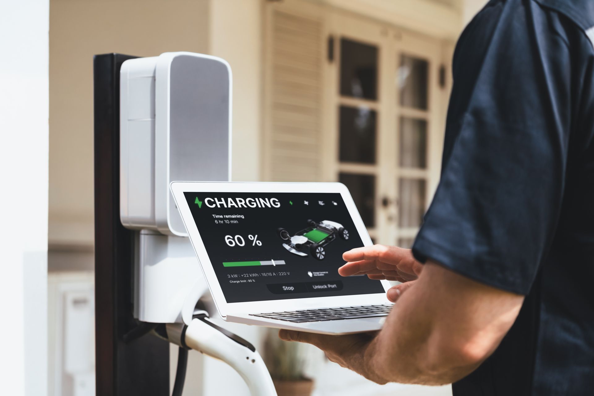 A man is holding a laptop in front of a charging station.