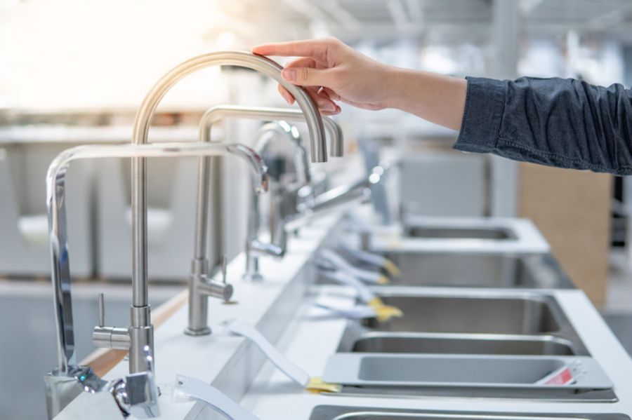Aprire manualmente un rubinetto di un lavello da cucina in acciaio inox con più vasche.